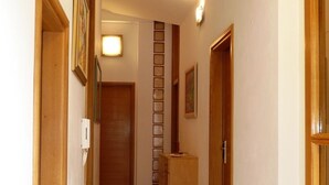 Un couloir avec des portes en bois, un petit meuble et un luminaire fixé au mur.