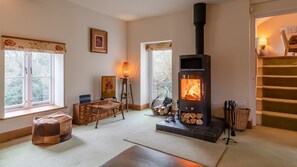 A cozy living room with a fireplace, wooden furniture, and a view of the outdoors.