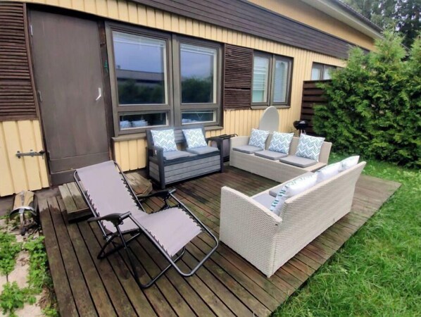 Relax on the patio with a comfortable lounge chair, sofa, and armchair, all facing a large window.