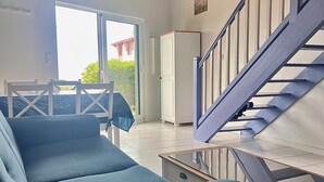 Una sala moderna con un sofá azul, una mesa de centro de vidrio y una escalera.