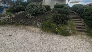 Una casa de dos pisos con entrada por una escalera de piedra y un camino de grava.