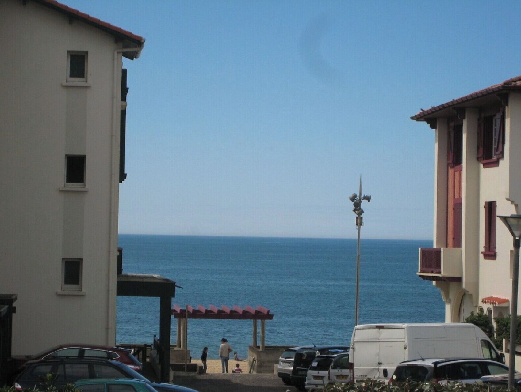 A coastal view with buildings, a pier, and a clear sky.