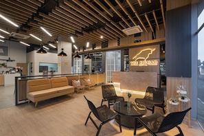 Welcome to our lobby, featuring a reception desk, comfortable seating area, and dining space with a round table.