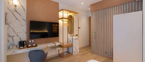 A modern hotel room with a large flat-screen TV, a wooden vanity, a marble-patterned wall, a bed, and a wardrobe with vertical stripes.