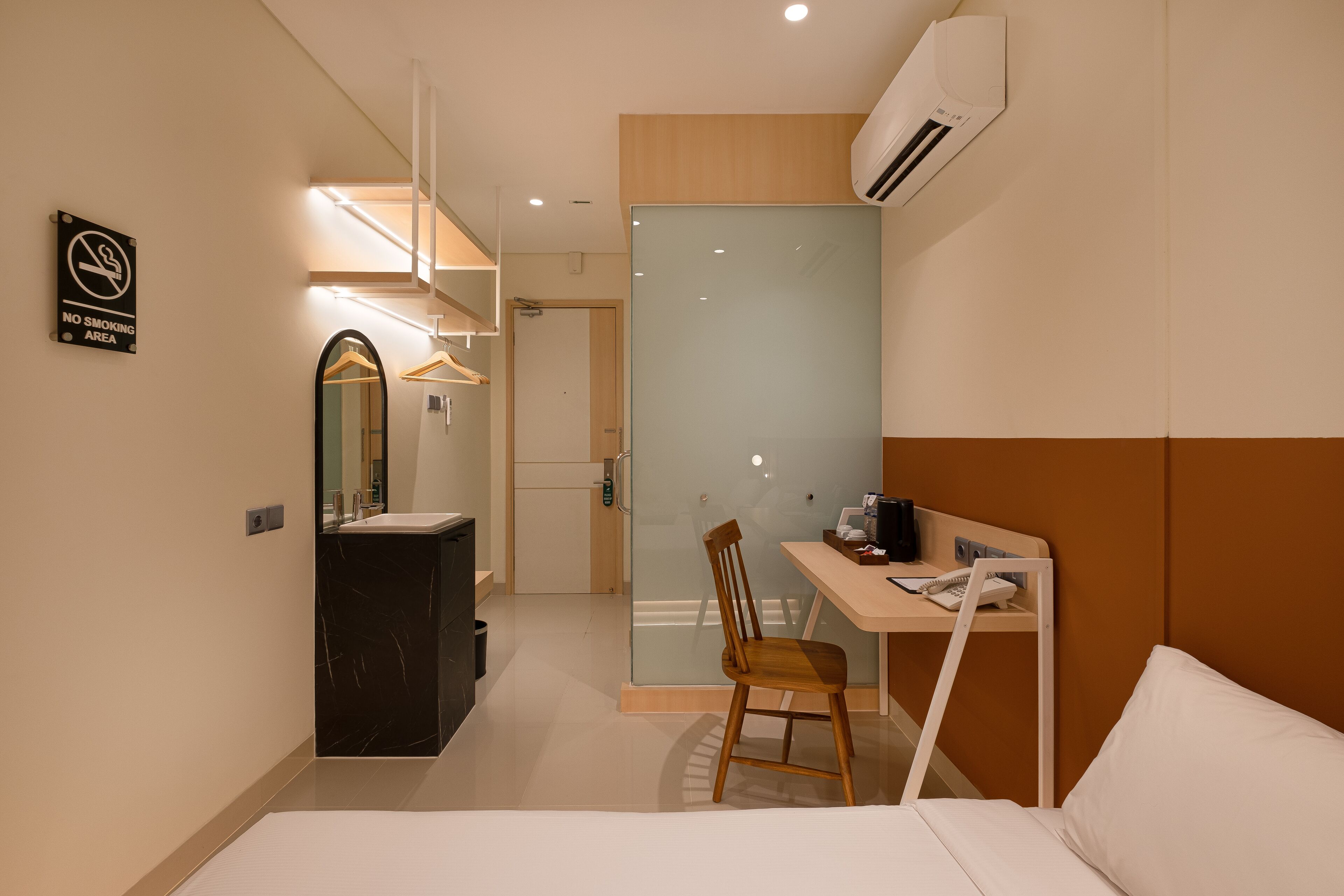 Habitación de hotel con cama, escritorio con silla, espejo, armario y baño con lavabo y espejo.