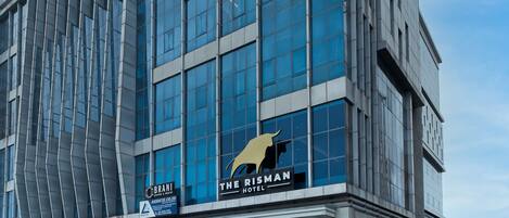 Un hotel moderno con un llamativo letrero que dice 'The Ritzman Hotel', con una amplia fachada de vidrio y un logotipo distintivo.