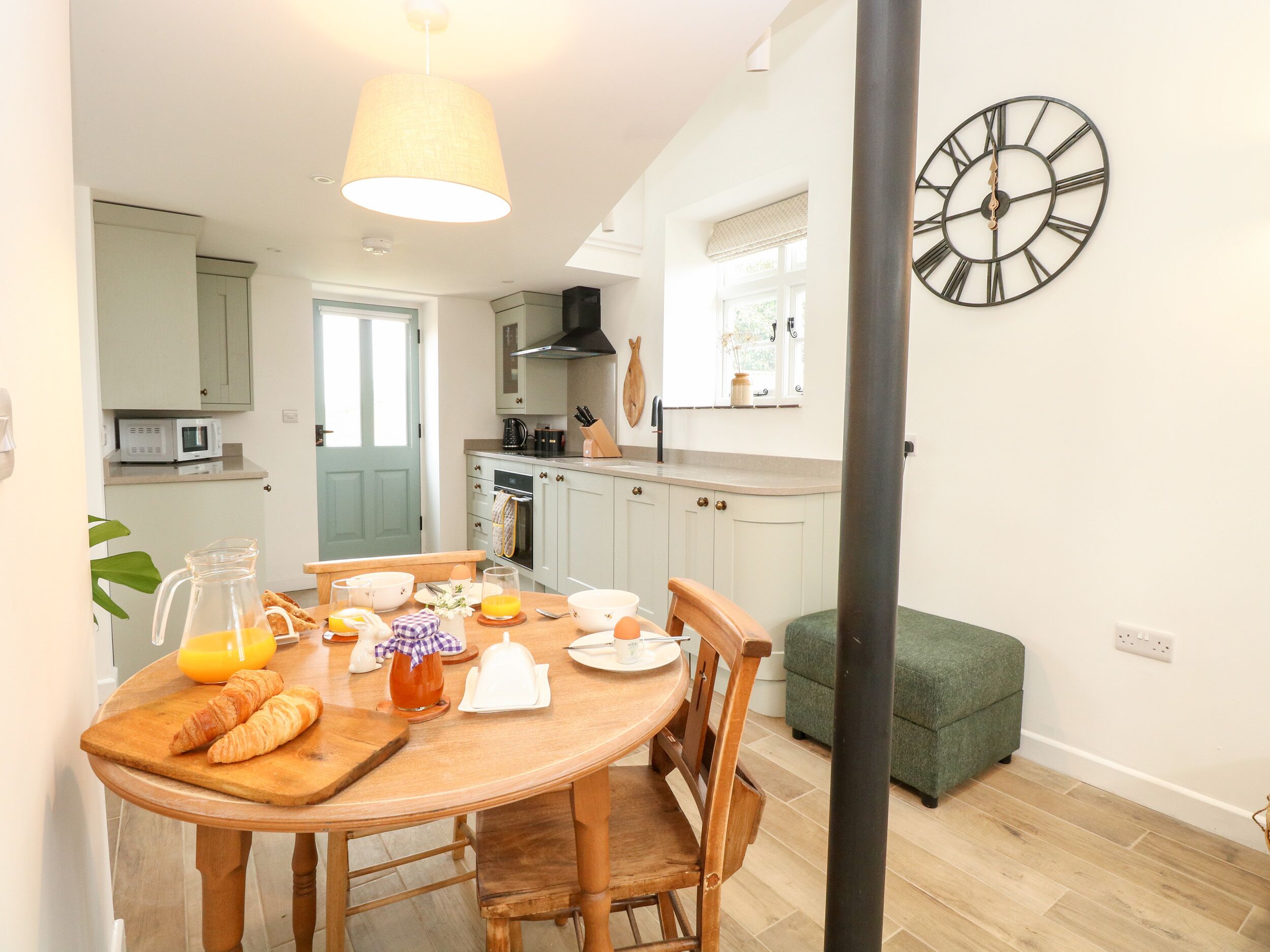 Un coin repas avec une table en bois, des chaises et une horloge au mur.