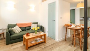 A cozy living room with a green sofa, a wooden coffee table, and a dining area with a wooden table and chairs. - Wensum Spring (Dereham)