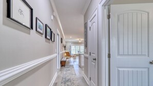 A hallway with framed artwork on the walls, a bench, and a door. - Links And Shore 406: 4  BR, 3  BA Condominium in Garden City, Sleeps 12 (Garden City)
