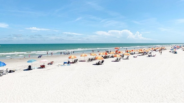 A beach with rows of sun umbrellas and lounge chairs, a clear sky, and the ocean in the background. - Links And Shore 406: 4  BR, 3  BA Condominium in Garden City, Sleeps 12 (Garden City)