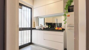 A modern kitchen with white cabinets, a black countertop, a microwave, and a refrigerator. - MOT Rentals + Anchorena 1400 - 2 Bd in Recoleta (Buenos Aires)