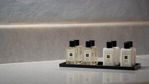 A display of Jo Malone London perfume bottles on a black tray against a textured wall. - Madame Kalitsi-ioli Standard Room (Santorini)