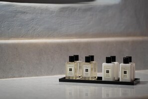 A display of Jo Malone London perfume bottles on a black tray against a textured wall.
