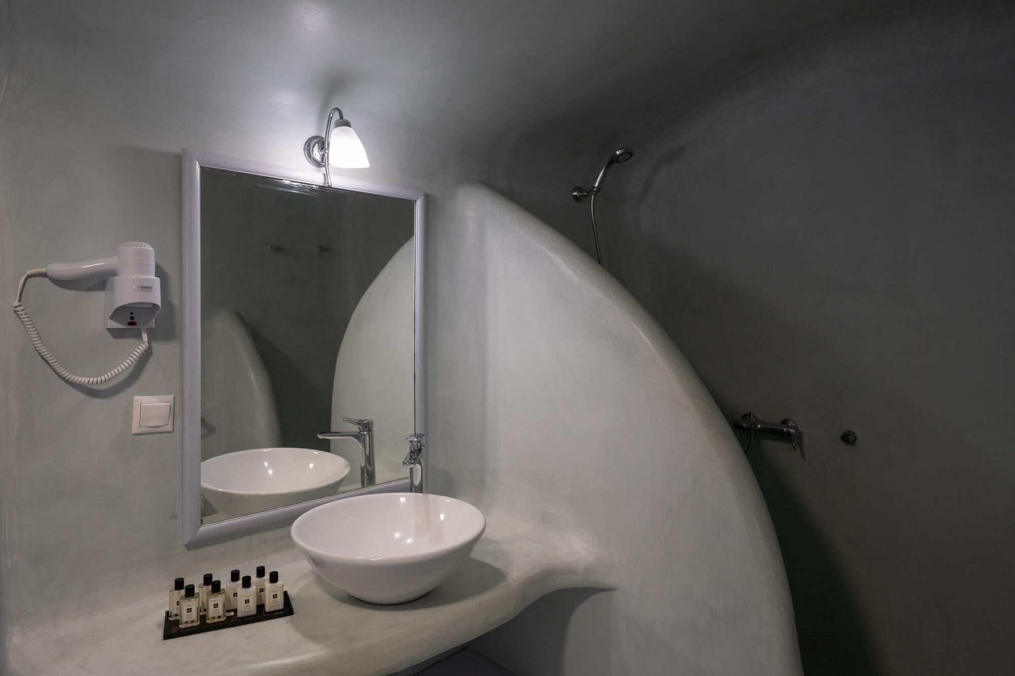 A bathroom with a white sink, a hairdryer, and a shower.