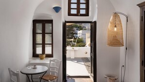 Una habitación con un arco de entrada blanco, una pequeña mesa con una silla, una lámpara colgante y vistas al exterior.