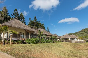 Un resort con villas de techo de paja, una piscina y exuberante vegetación.