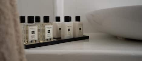 En hylla i badrummet med flera flaskor av Jo Malone Londons produkter.