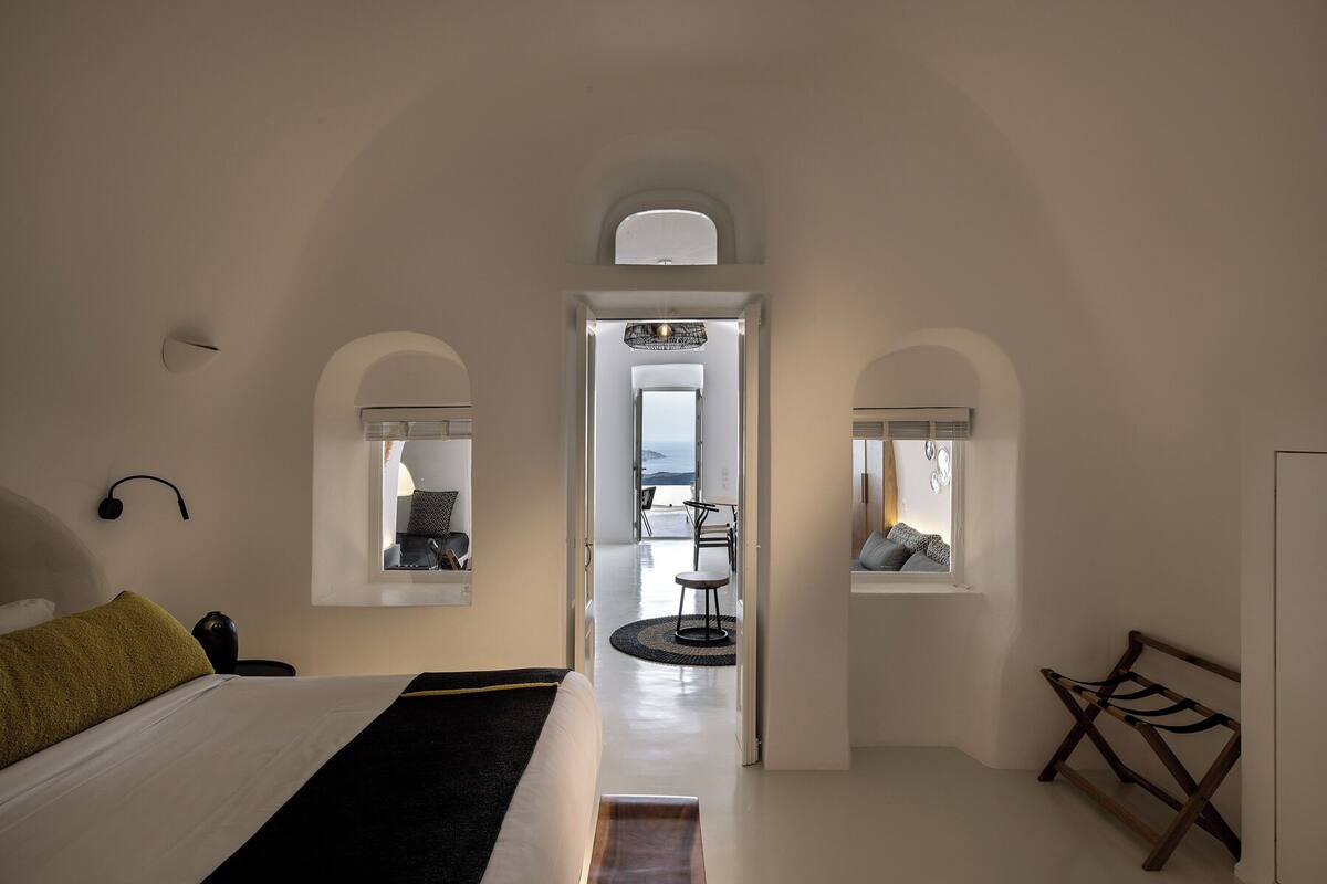 A bedroom with a bed, a bedside table, and a window with a view.