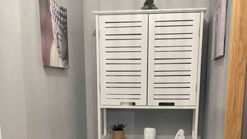 Een kleine badkamer met toilet, een klein plankje met decoratieve spullen en een vloer met patroon.