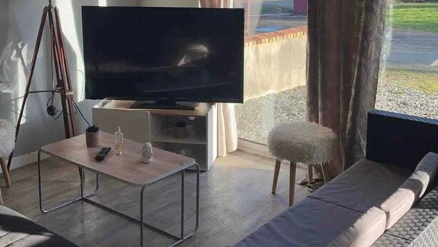 A living room with a television, a lamp, a sofa, and a window with curtains. - T2 in the countryside near greenway. (Banvou)
