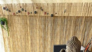 A wicker outdoor seating area with a table and chairs, a decorative head sculpture, and a bamboo backdrop. - T2 in the countryside near greenway. (Banvou)