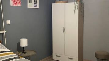 A bedroom with a bed, a wardrobe, a bedside table, a lamp, and a ceiling light fixture.