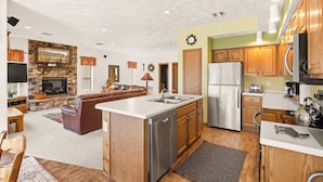 A modern kitchen with a central island, wooden cabinets, and stainless steel appliances. - Seven Springs 4 BR Premium Condo, Mountain Views! by RedAwning (Champion)