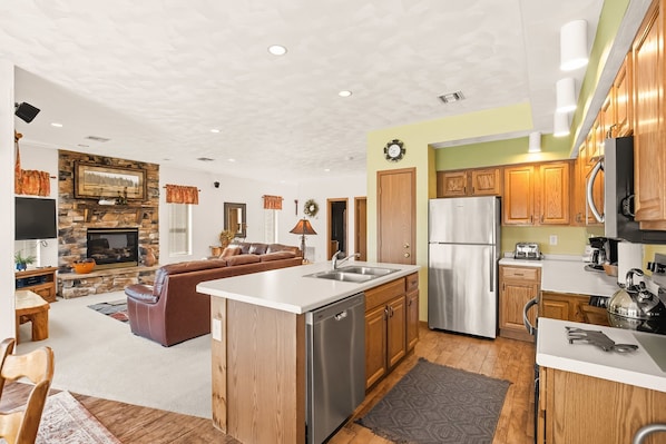 A modern kitchen with a central island, wooden cabinets, and stainless steel appliances.