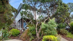 A modern house with a sloped roof, surrounded by lush greenery and a well-maintained garden. - Moonah Horizon (Rye)