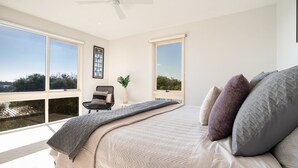 A bedroom with a large bed, a ceiling fan, and a view of the outdoors through large windows. - Moonah Horizon (Rye)