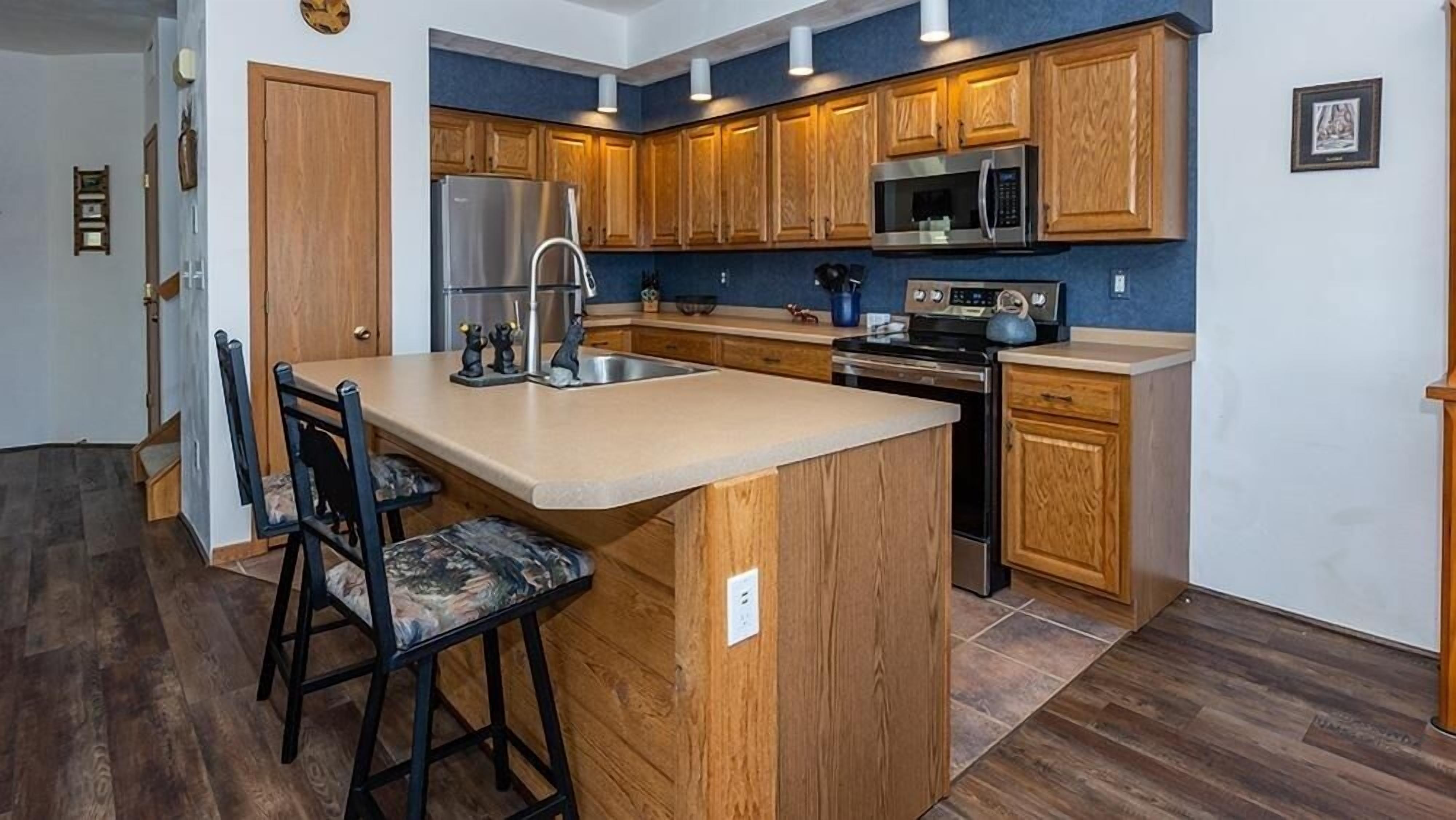 A modern kitchen with wooden cabinets, stainless steel appliances, and a central island with bar stools.