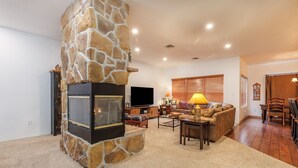 A living room with a stone fireplace, a sofa, a coffee table, and a TV. - Seven Springs 4 BR Premium Condo, Deck with Views by RedAwning (Champion)