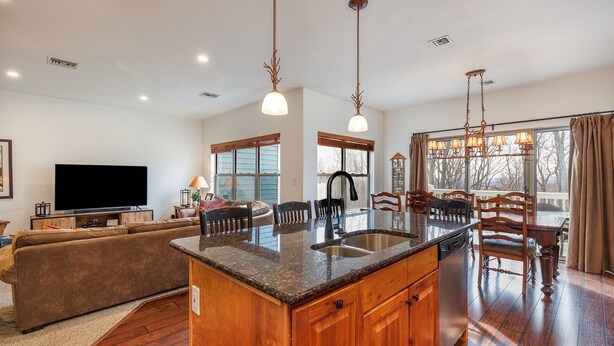 A spacious living room with a large TV, a wooden dining table, and a kitchen island with granite countertops. - Seven Springs 4 BR Premium Condo, Deck with Views by RedAwning (Champion)
