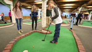 An indoor miniature golf course with players and a putting green. - Seven Springs 4 BR Premium Condo, Deck with Views by RedAwning (Champion)