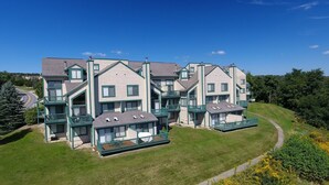 A multi-story residential building with a central courtyard, balconies, and a sloped roof. - Seven Springs 2 BR Condo - Deck and Mountain Views by RedAwning (Champion)