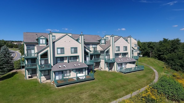 A multi-story residential building with a central courtyard, balconies, and a sloped roof.