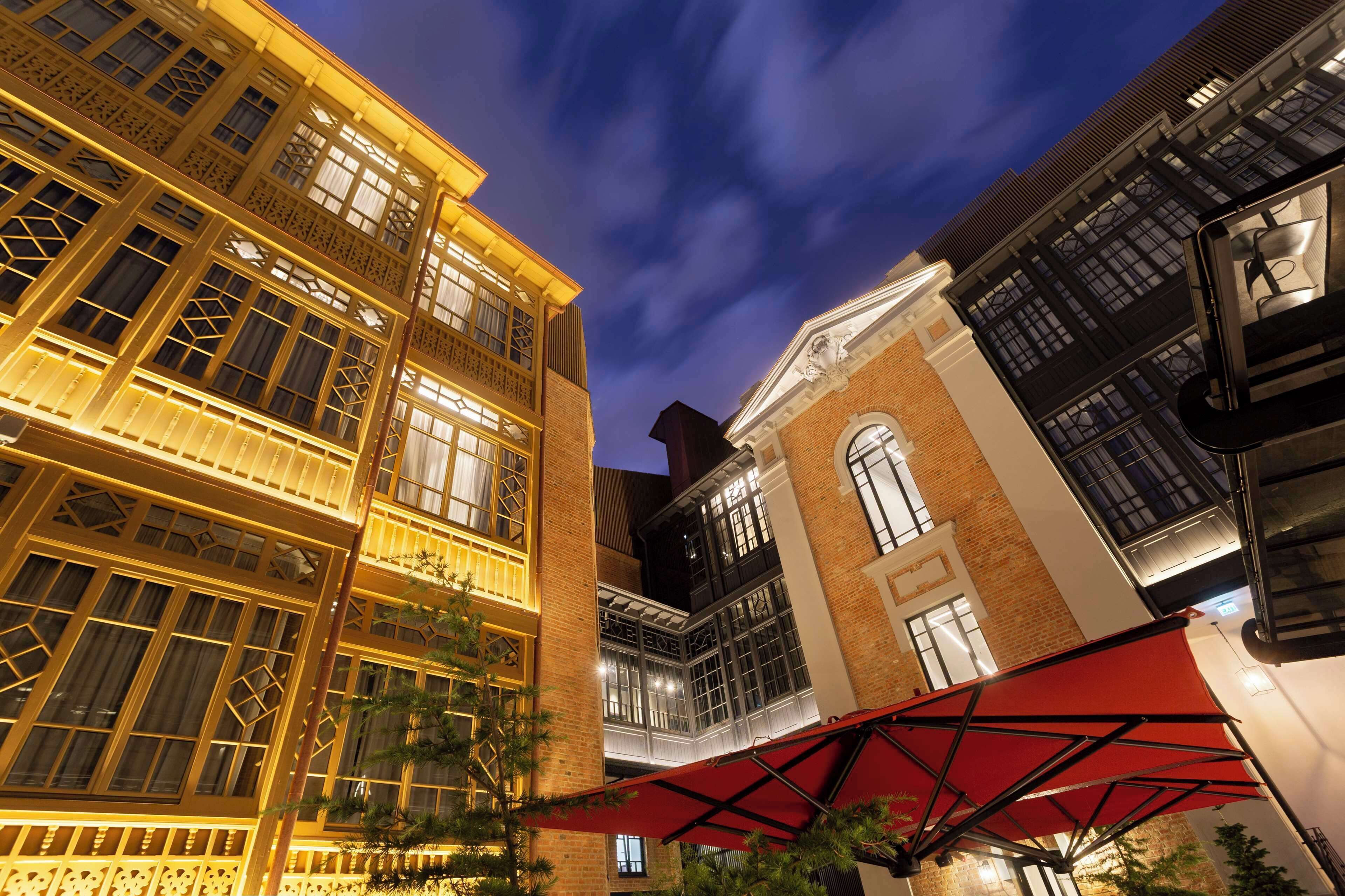 A multi-story building with illuminated windows and a red awning.