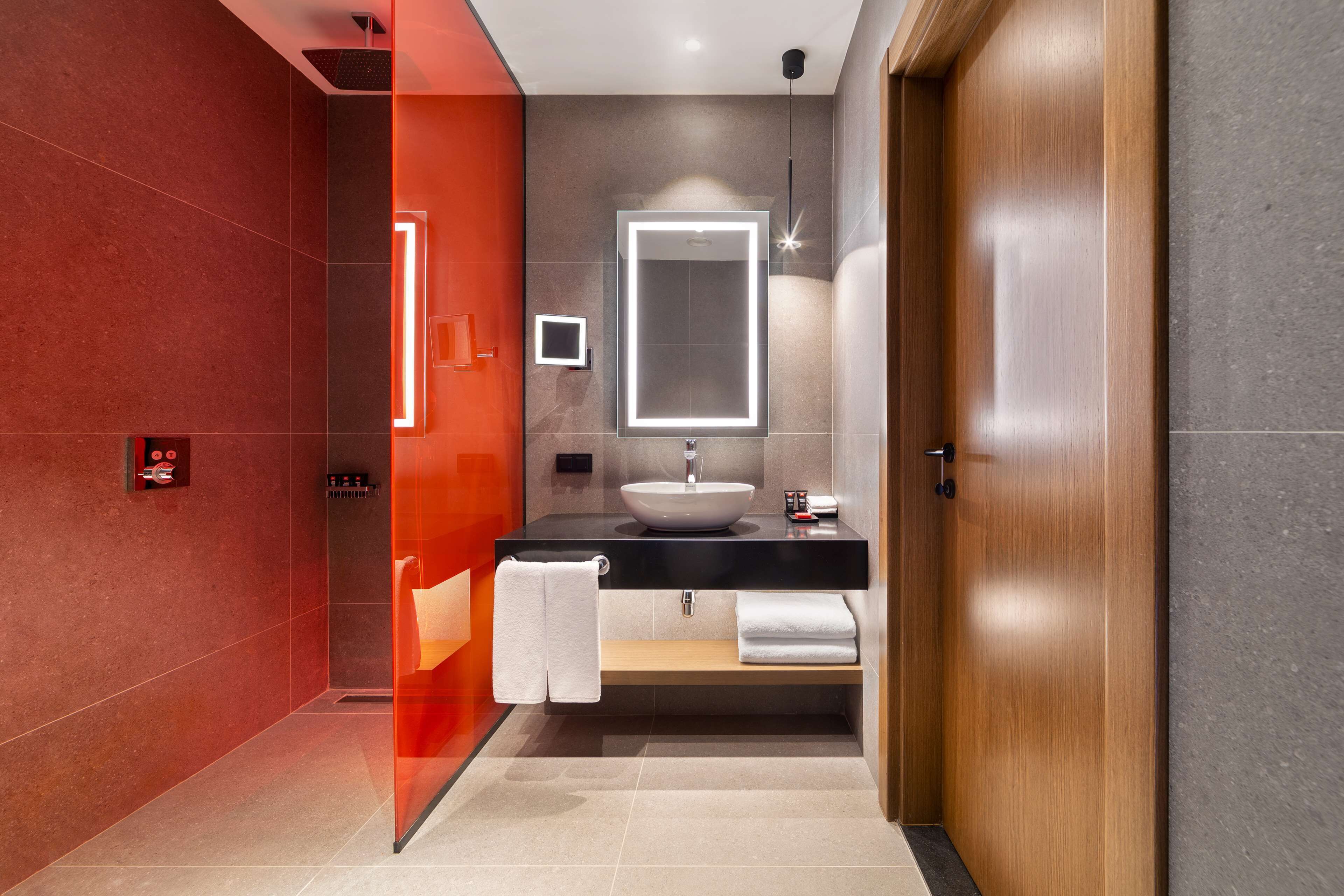 A modern bathroom with a large mirror, a sink, and a towel rack.