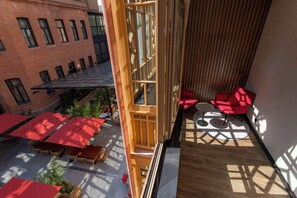 A high-rise building with a rooftop terrace featuring red umbrellas and outdoor seating.