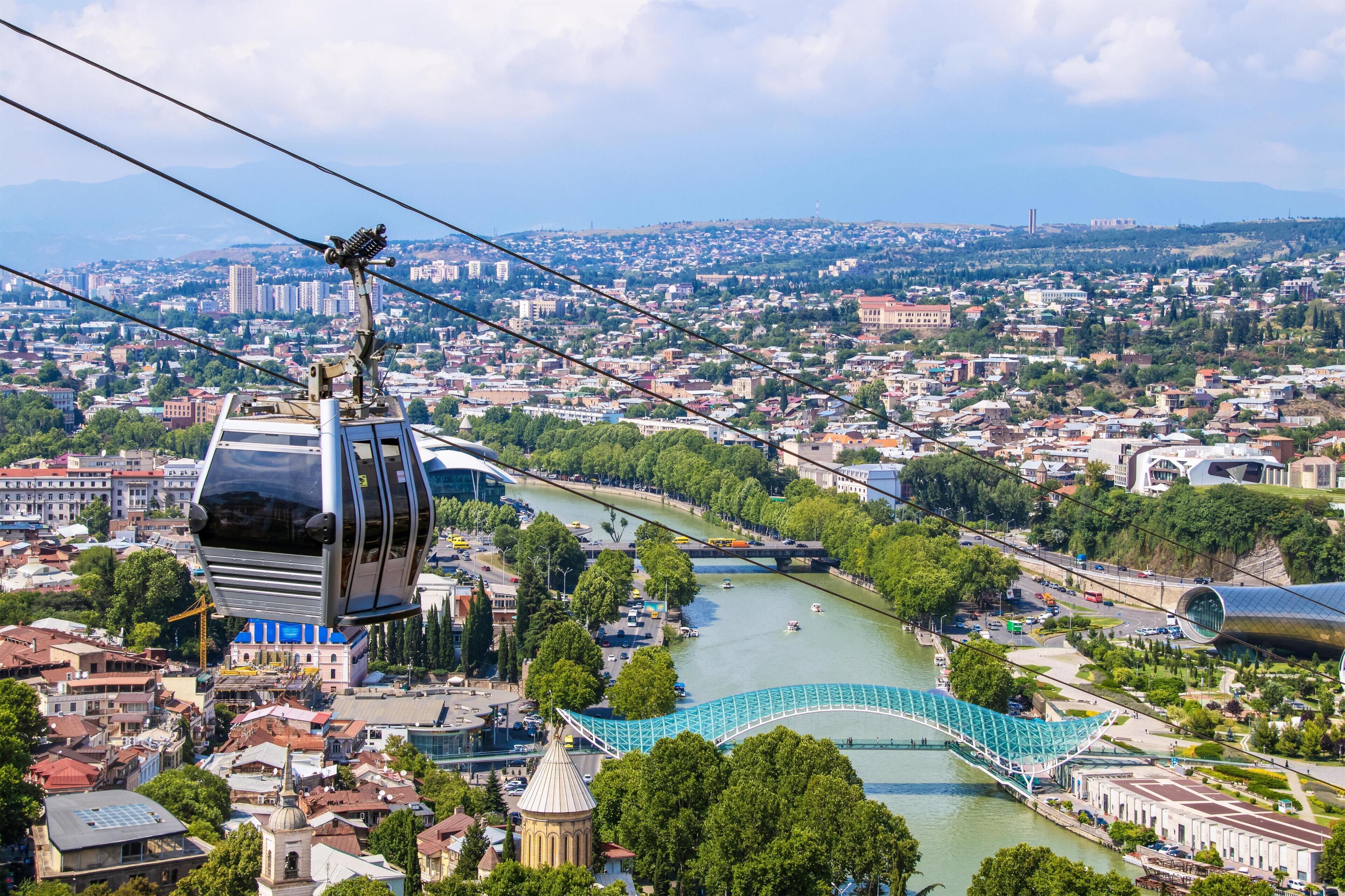 A cable car system, a river, and a cityscape with buildings and greenery.