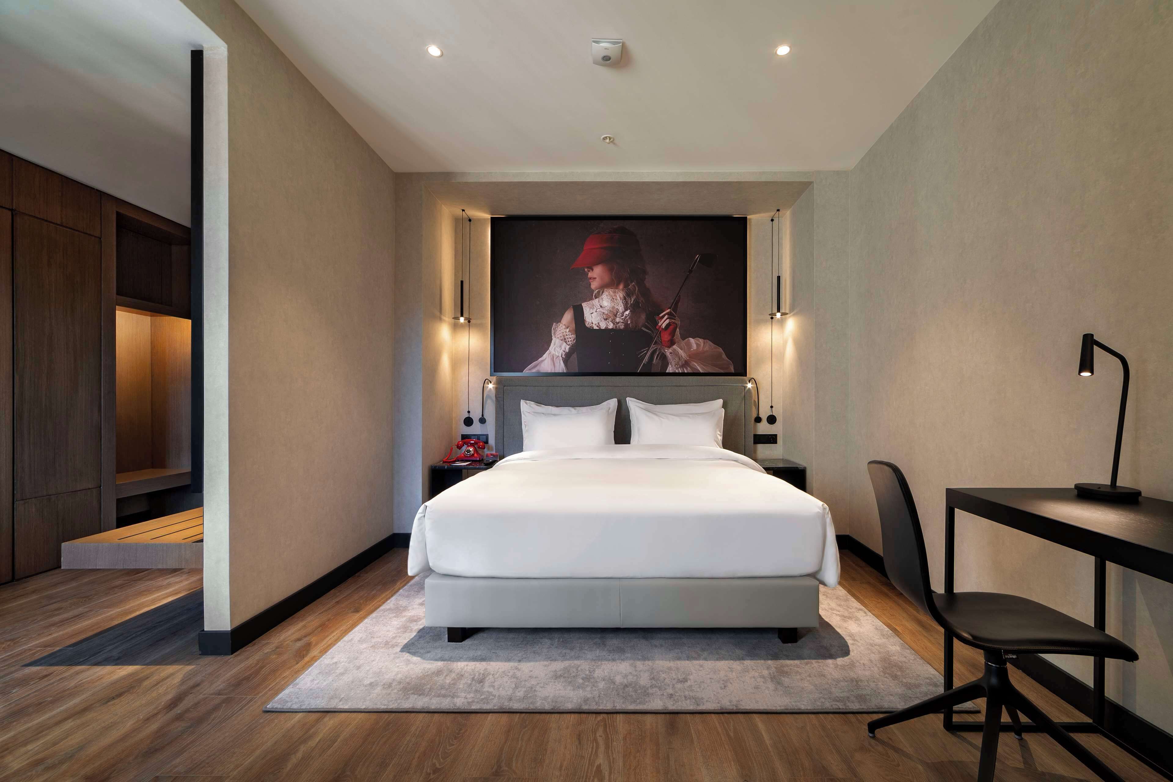 A modern bedroom with a large bed, a desk, and a chair.