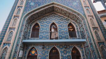 A building with intricate blue and beige tile patterns, arched windows, and a balcony with a railing.