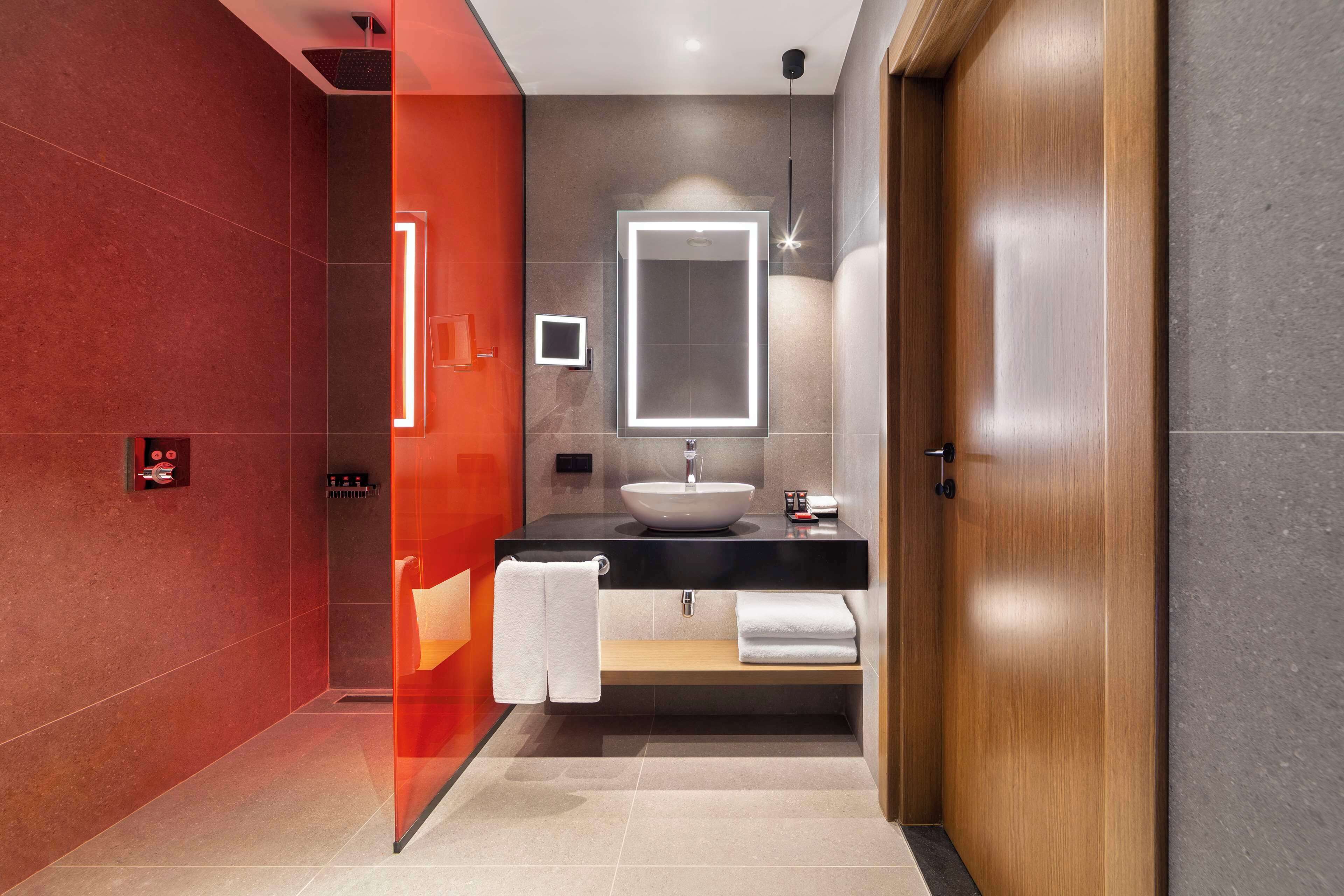 A modern bathroom with a large mirror, a sink, and a towel rack.