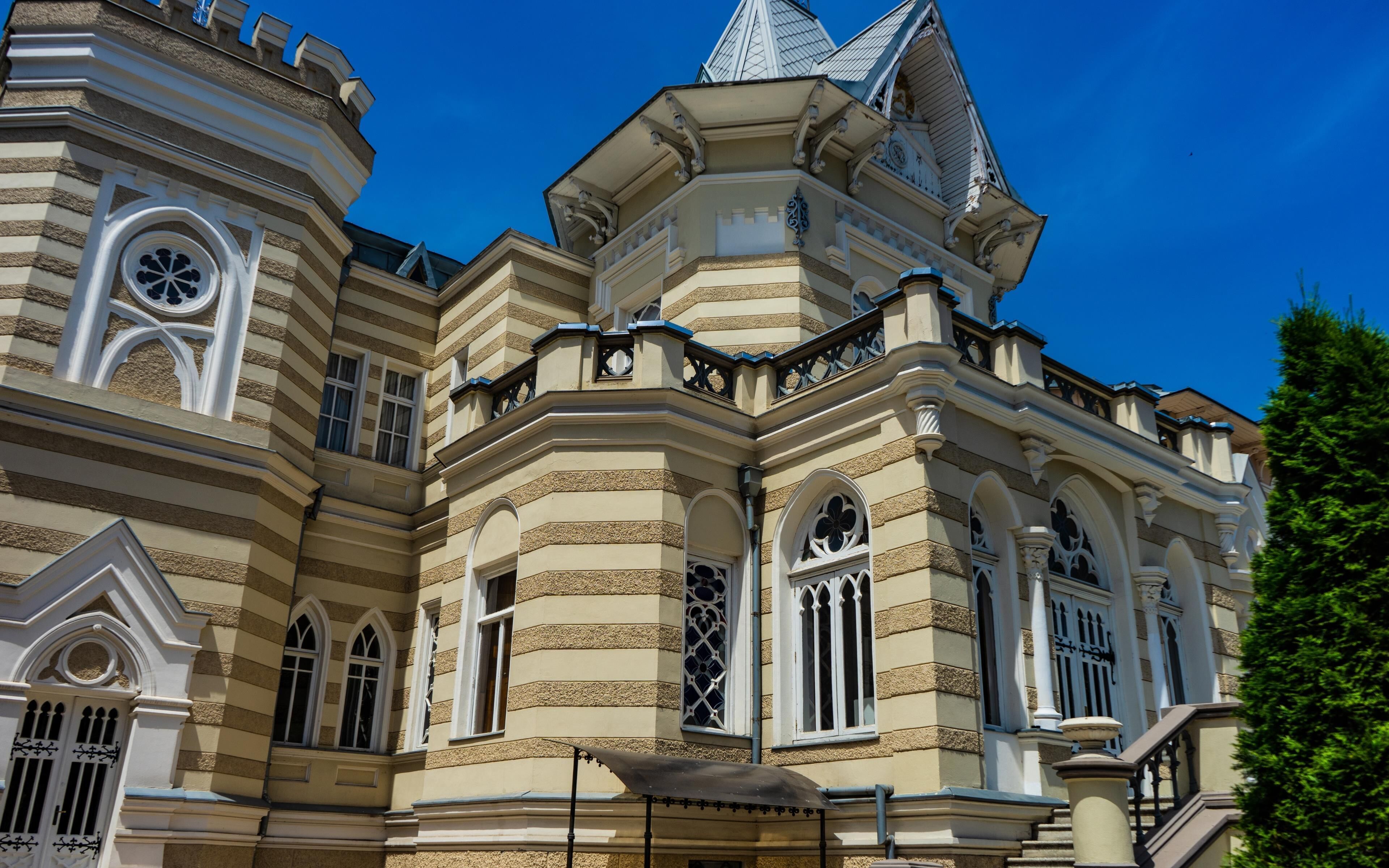 Un edificio histórico con arquitectura ornamentada, que incluye una torre y ventanas de arco.
