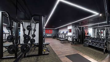 A modern gym with various exercise equipment, treadmills, and weight racks.