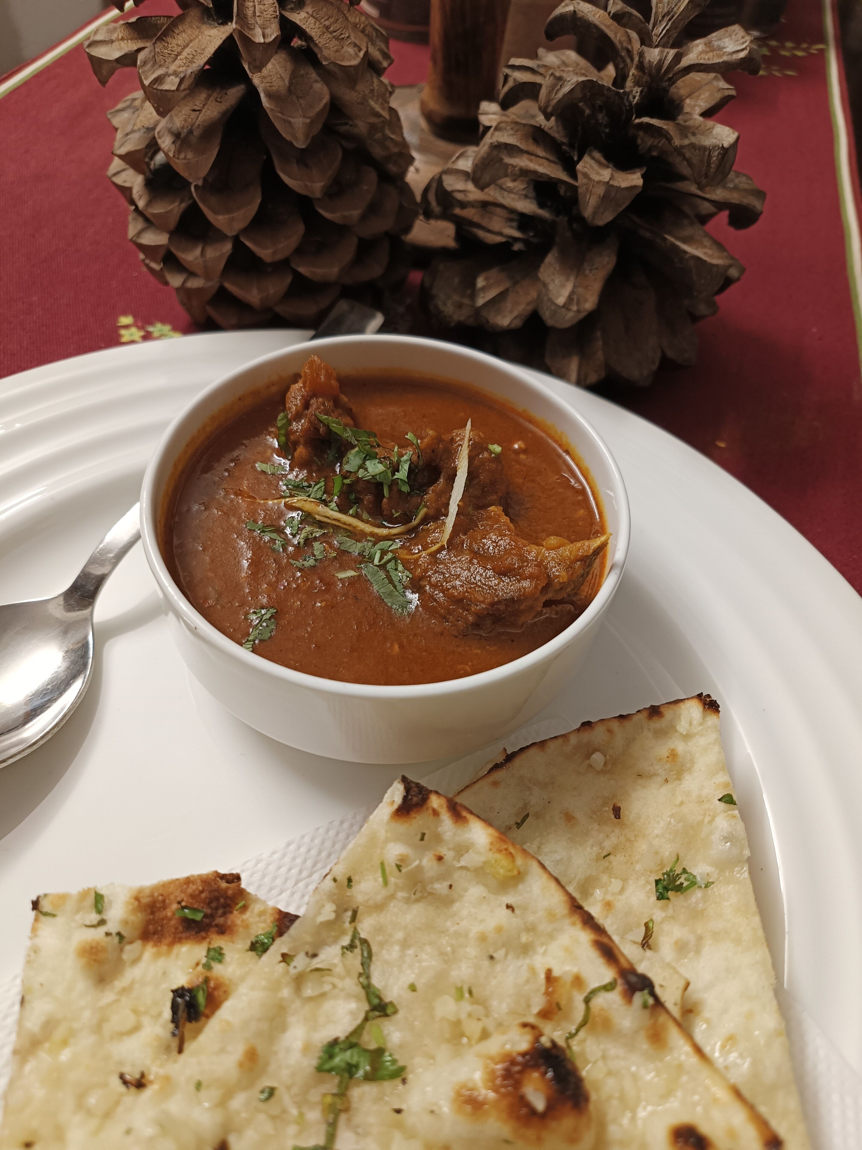A bowl of curry with naan bread on a white plate.
