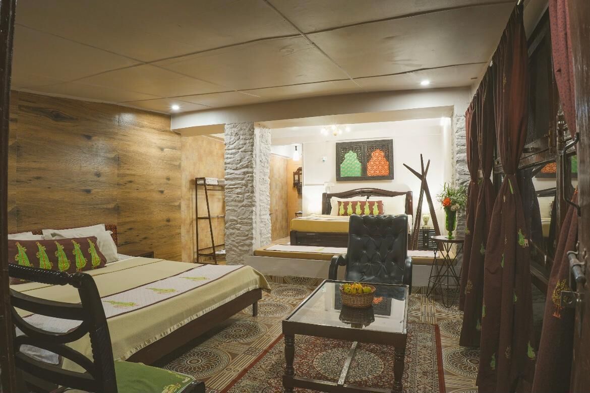 A cozy room with a bed, a chair, a table, and a small seating area with a table and chairs.