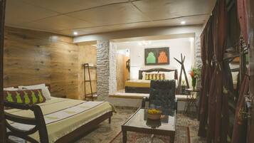 A cozy room with a bed, a chair, a table, and a small seating area with a table and chairs.