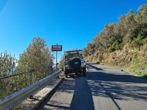 Ein weißer SUV fährt auf einer Straße, neben der ein Schutzschild ist. Ein Schild mit der Aufschrift 'PREVO' ist ebenfalls zu sehen.