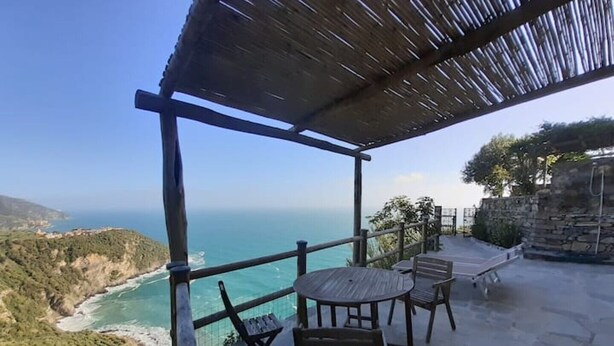 A terrace with a view of the sea and hills, featuring a table and chairs. - Lemon Suite - Prevo Cinque Terre (Vernazza)